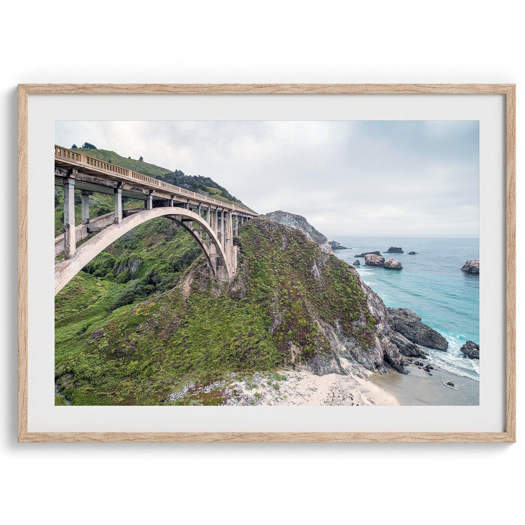 A fine art ocean print of one of the most iconic spots in the famous Route 1 in California - Bixby Bridge near Big Sur. Shot in a unique wide angle that captures the bridge, cliffs, the ocean, and the stunning beach below.