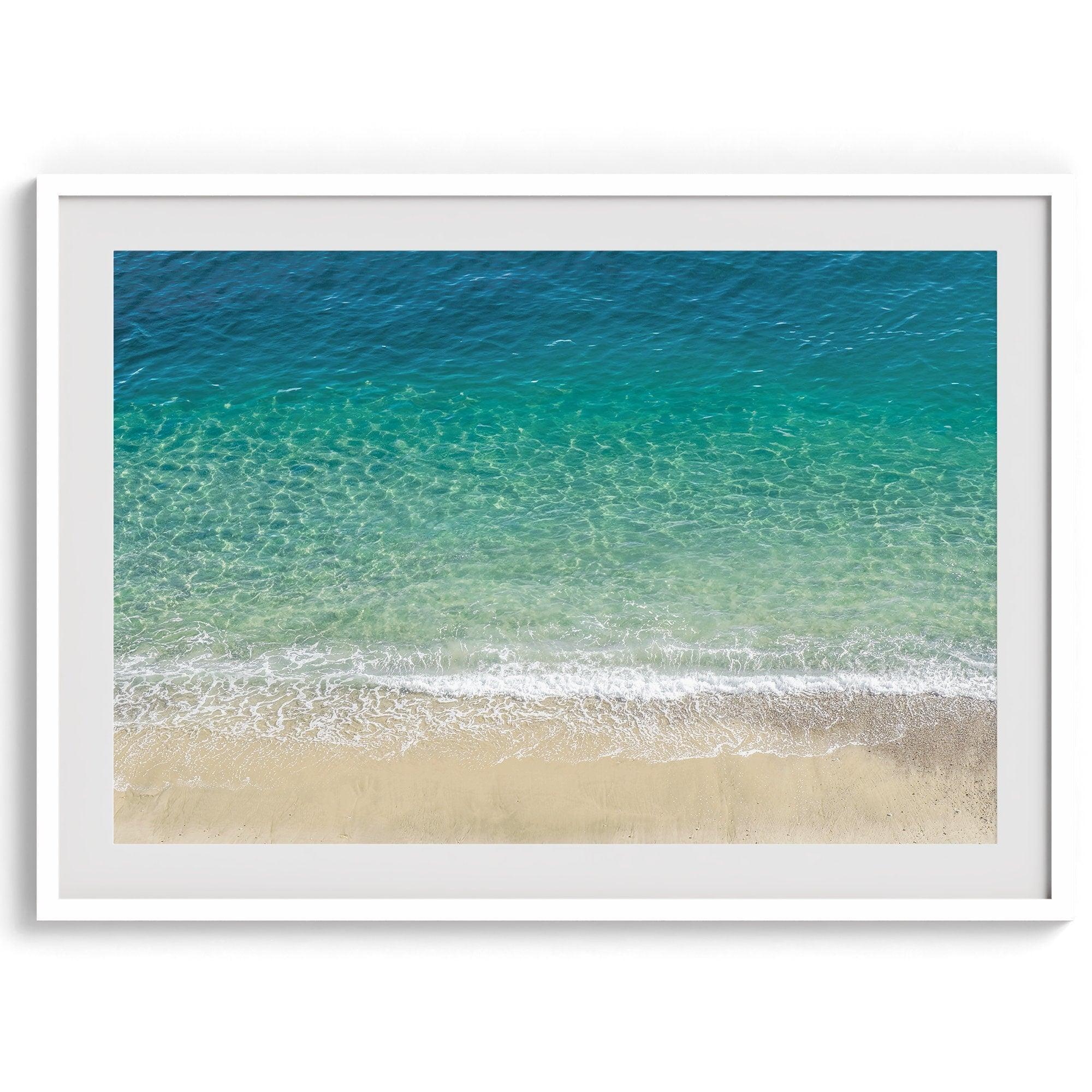 This fine art aerial beach print showcases the mesmerizing colors of the ocean in vivid detail. From the deep blue depths to the vibrant greenish turquoise blue, transitioning to the golden sandy beach and the crashing white surf.