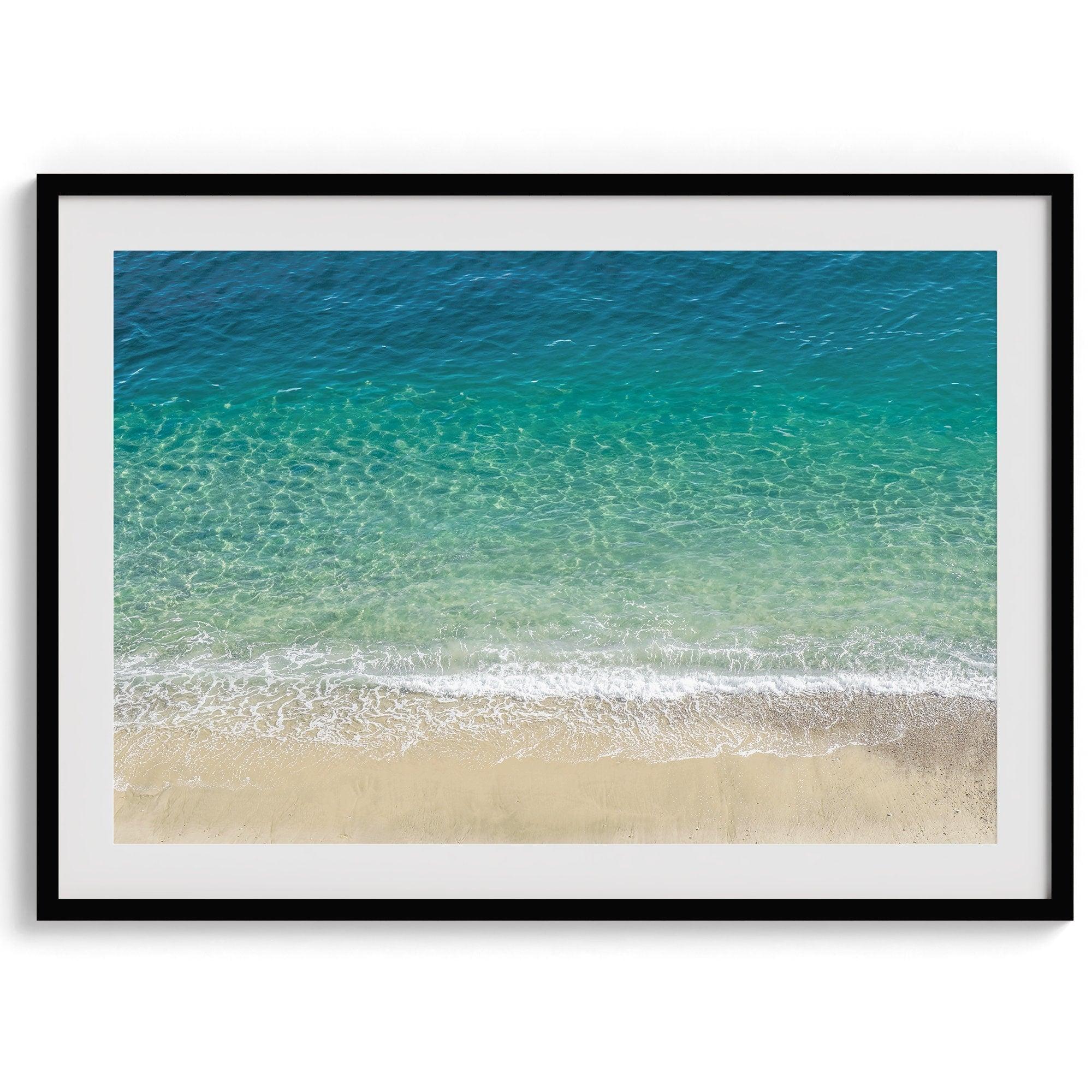 This fine art aerial beach print showcases the mesmerizing colors of the ocean in vivid detail. From the deep blue depths to the vibrant greenish turquoise blue, transitioning to the golden sandy beach and the crashing white surf.