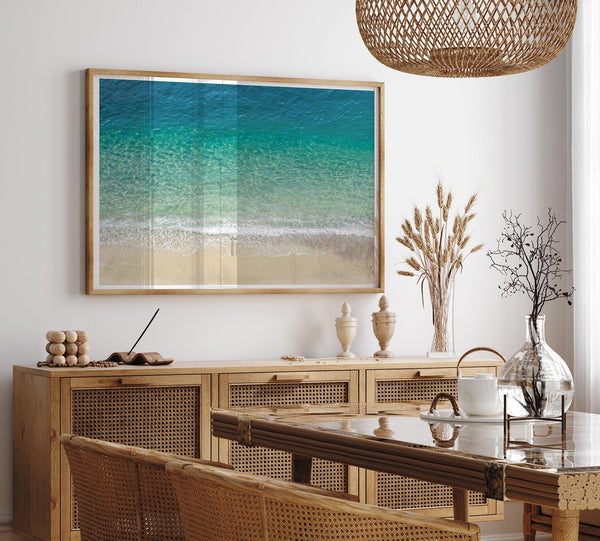 This fine art aerial beach print showcases the mesmerizing colors of the ocean in vivid detail. From the deep blue depths to the vibrant greenish turquoise blue, transitioning to the golden sandy beach and the crashing white surf.