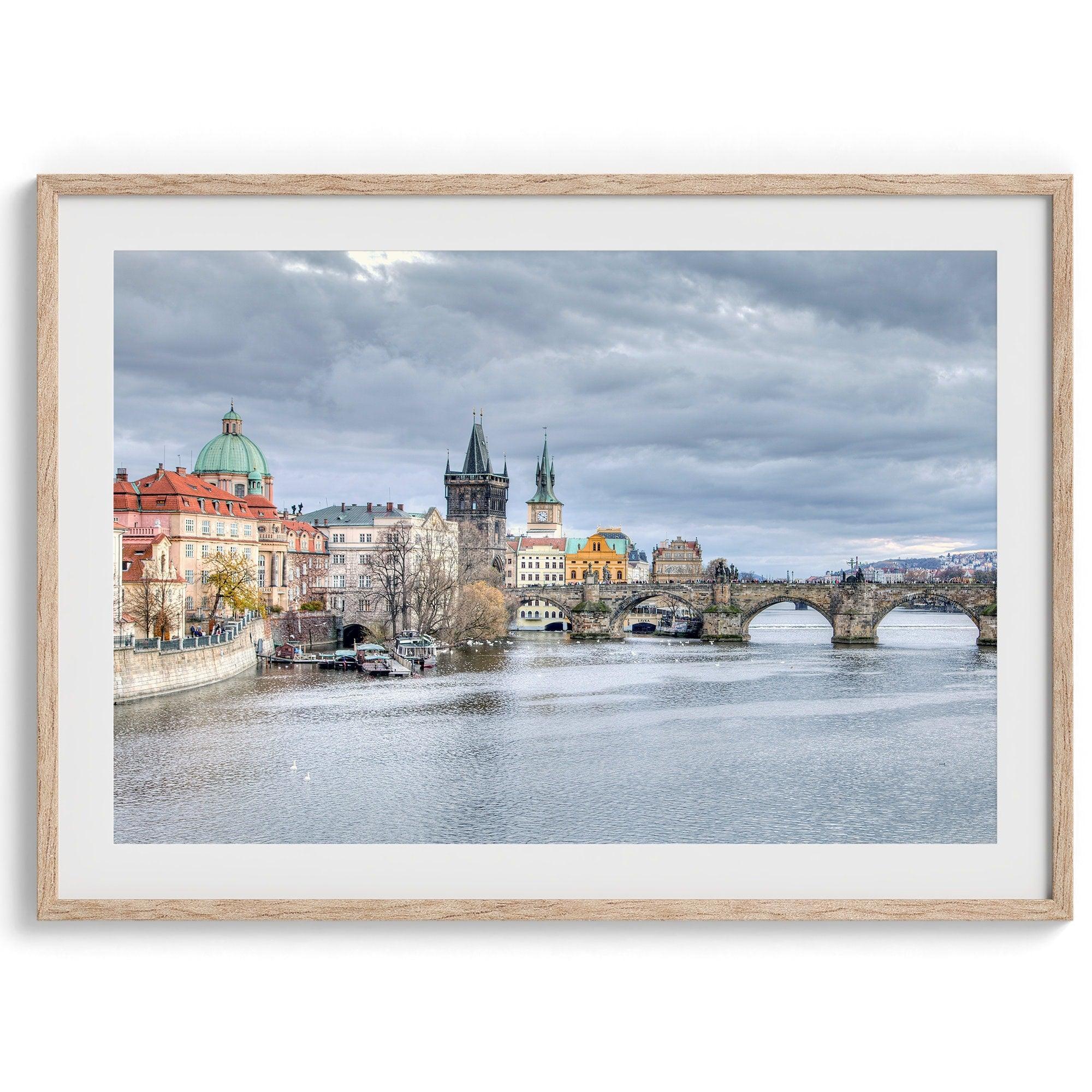 This Prague wall art is a fine art photography print of Charles Bridge against a moody skyline, evoking an old-world painting. Timeless allure captured on archival paper, available in various sizes and frames.