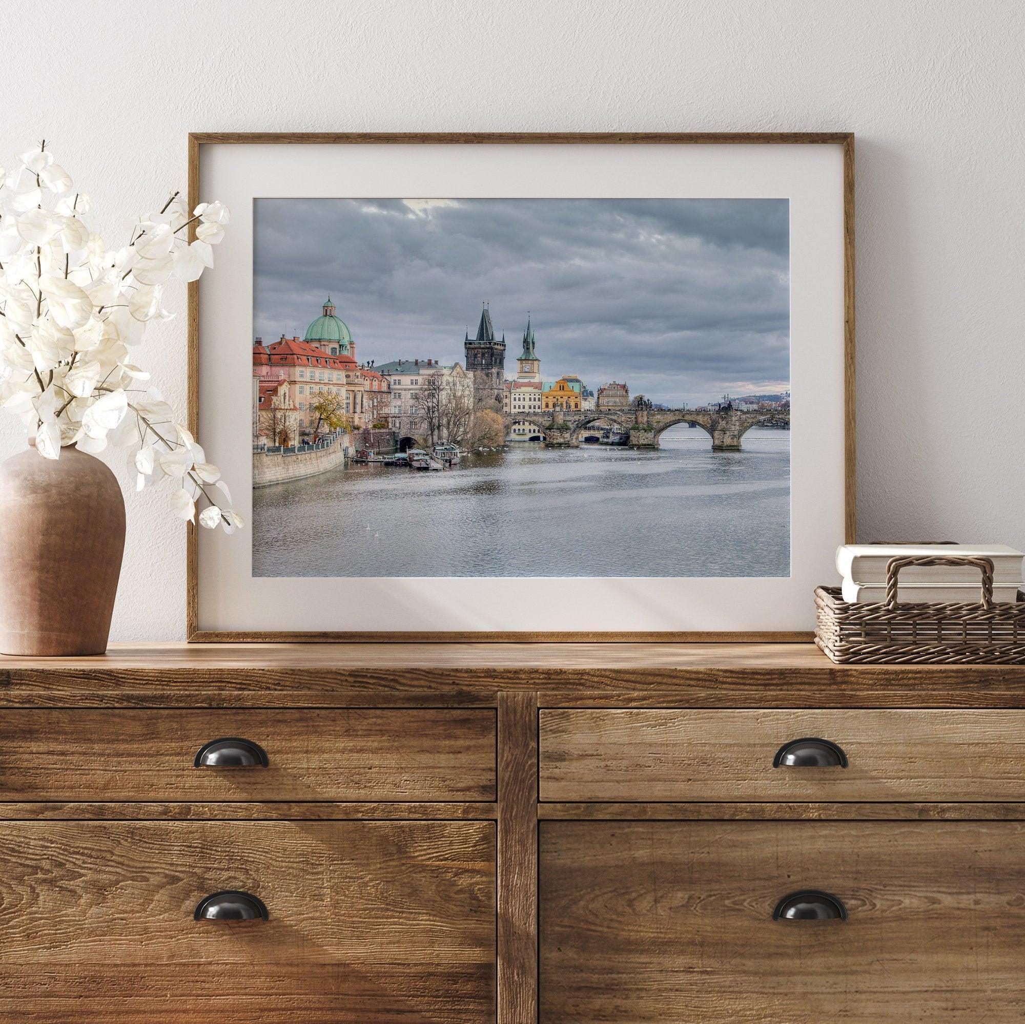 This Prague wall art is a fine art photography print of Charles Bridge against a moody skyline, evoking an old-world painting. Timeless allure captured on archival paper, available in various sizes and frames.