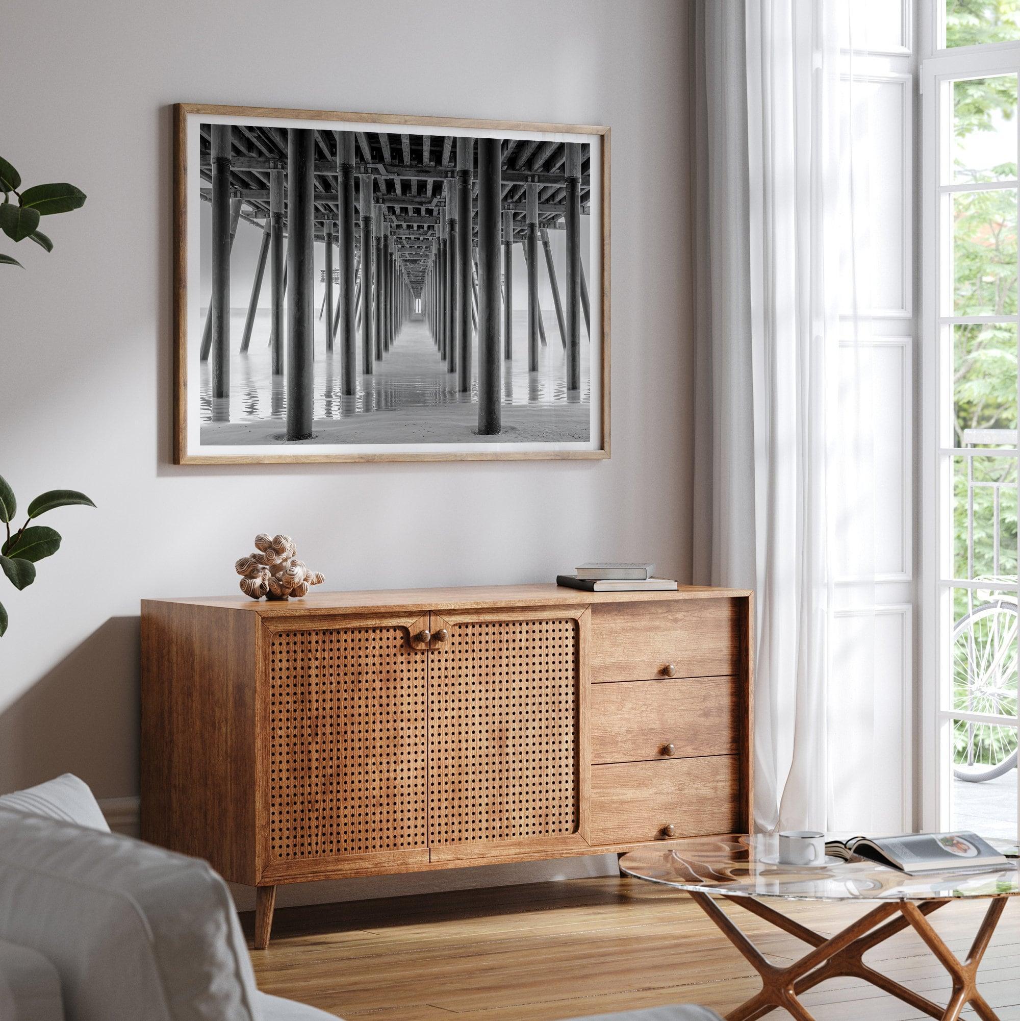 A large fine art abstract black and white beach pier print This stunning beach wall art shows the symmetric structure of the pier with the ocean water gently caressing the pier and beach.