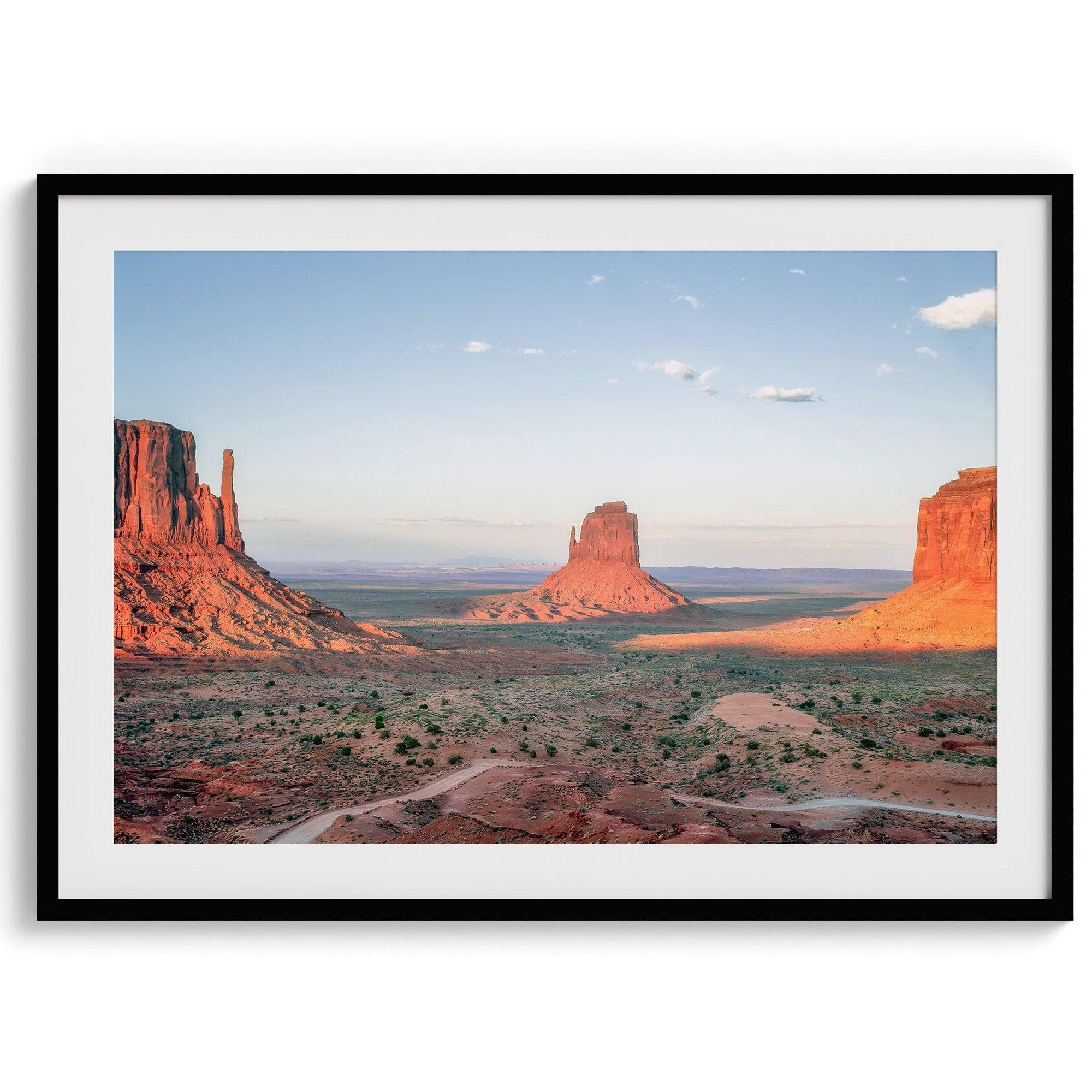 A fine art landscape photography print of a desert sunset over Monument Valley, located on the Arizona-Utah border. The warm and vibrant hues of this American Southwest sunset create a mesmerizing and awe-inspiring scene.