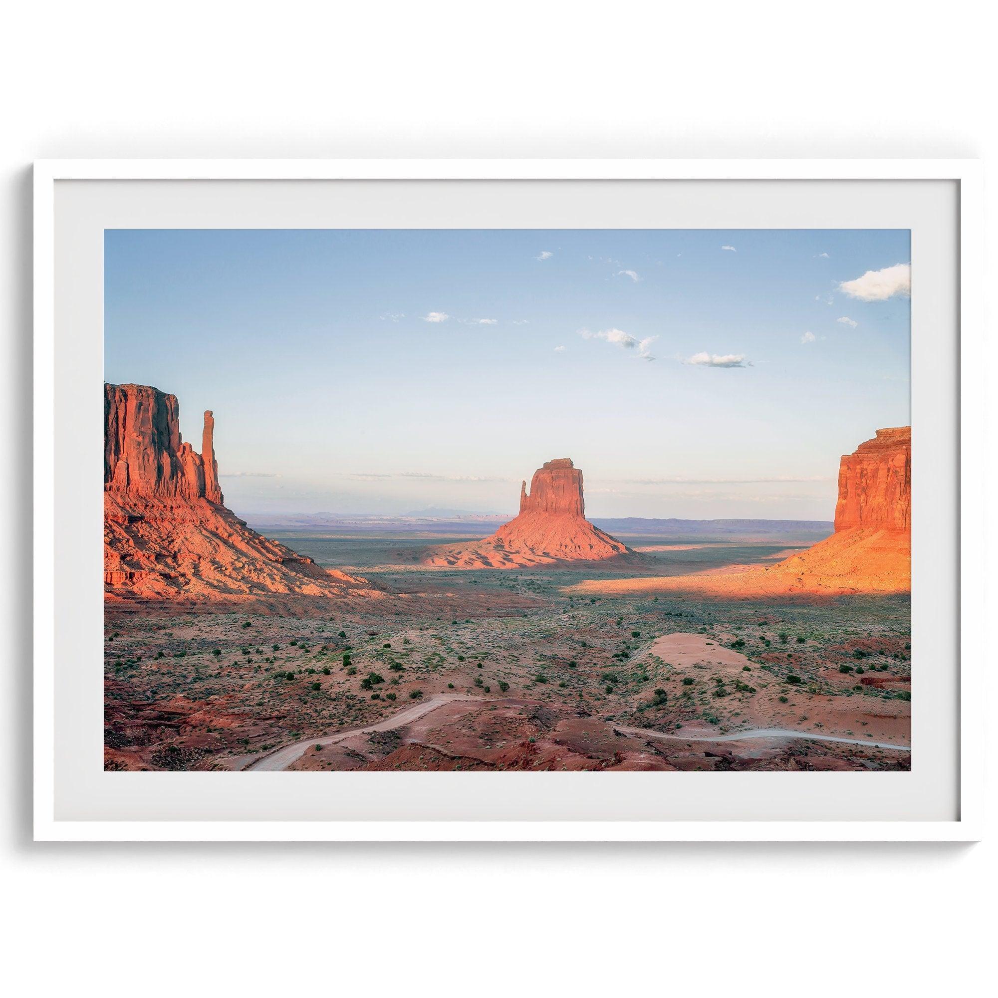 A fine art landscape photography print of a desert sunset over Monument Valley, located on the Arizona-Utah border. The warm and vibrant hues of this American Southwest sunset create a mesmerizing and awe-inspiring scene.