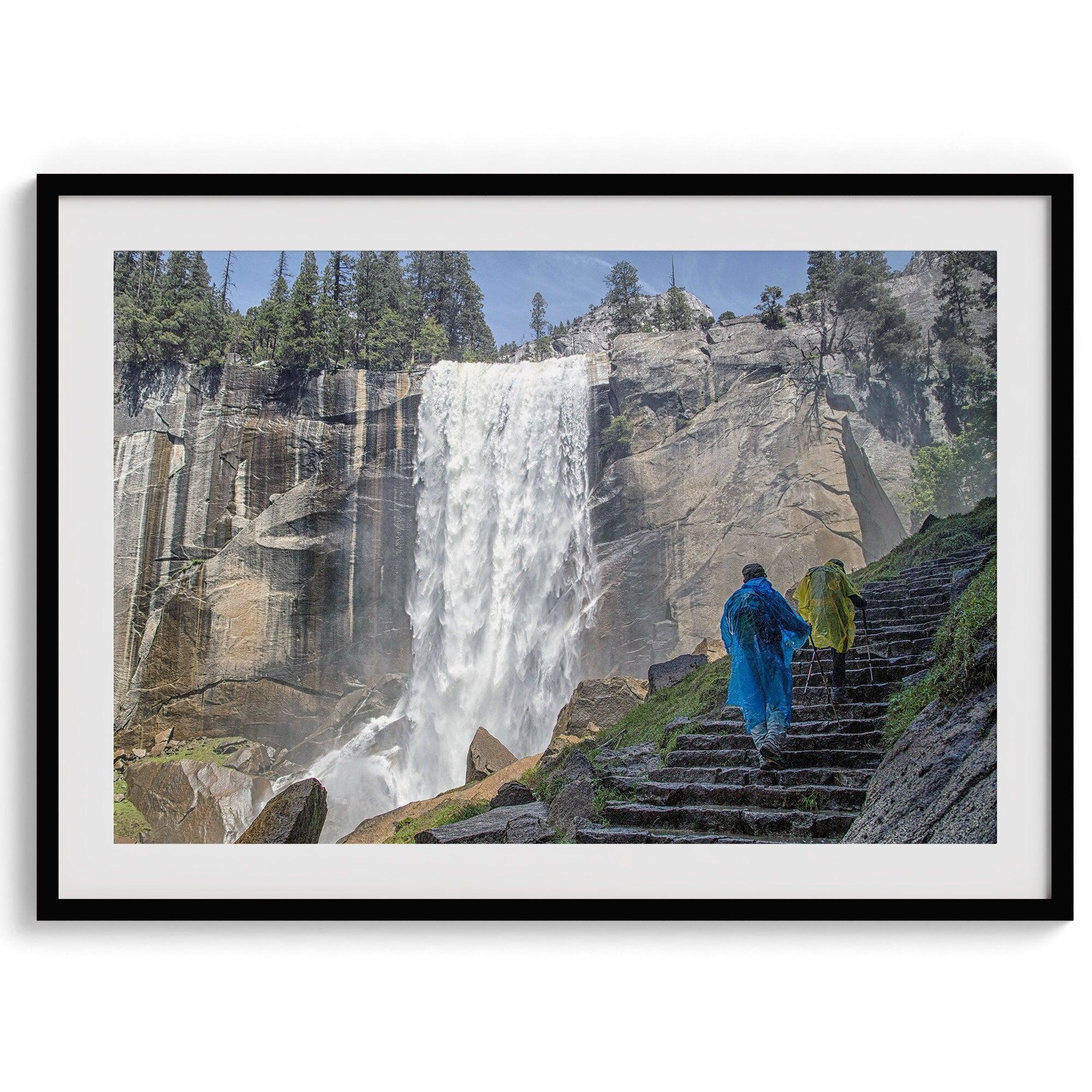 Climb the breathtaking Mist Trail in Yosemite National Part with this fine art waterfall nature print. This nature landscape wall art showcases the stunning gushing waterfall and the people scaling the trail with their colorful raincoats.