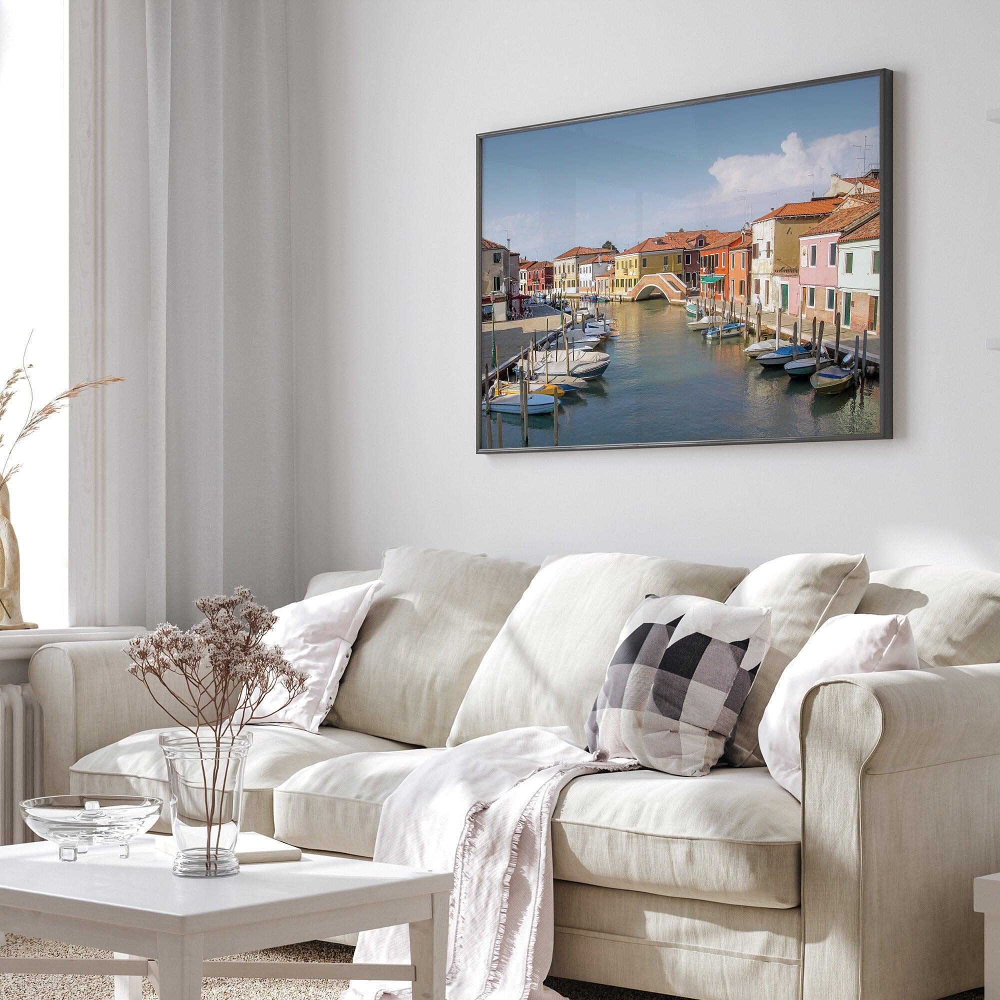 A stunning framed Venice print. The picturesque vibrant streets of Murano are lined with houses in an array of vibrant colors. The sun casts a beautiful glow on the tranquil canal, which adds to the charm of this peaceful Italian town.