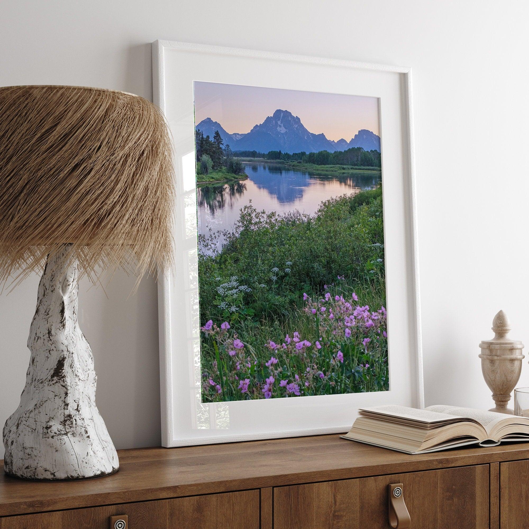 A fine art framed or unframed mountain print of Grand Teton National Park. This portrait orientation nature landscape wall art showcases the beautiful Teton mountains in a pink sunset, with Snake River and stunning flowers in the forefront.