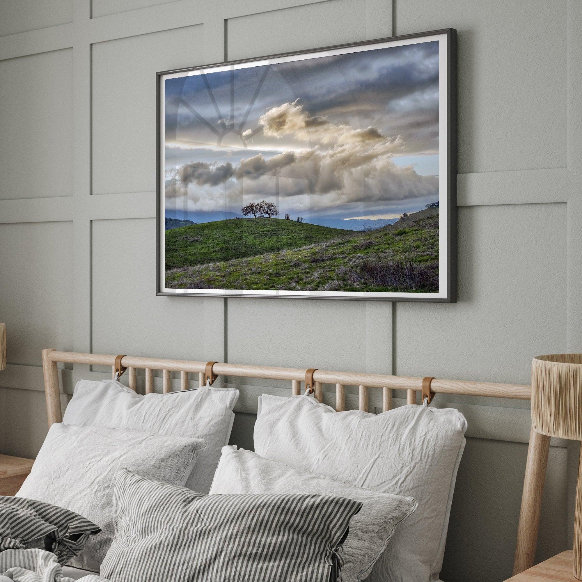 A fine art California moody landscape photography print showing a lone tree standing atop a hill against a dramatic cloudy sky in this scenic landscape wall art.