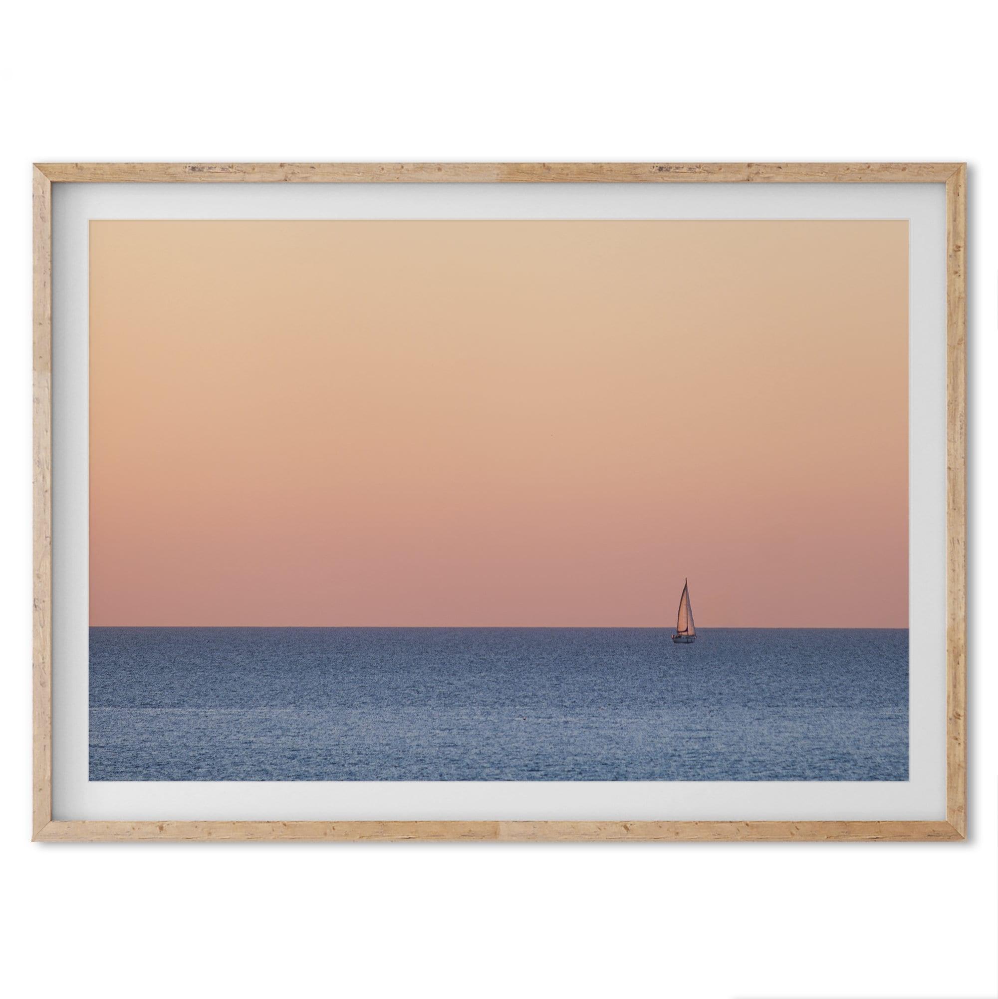 This stunning fine art ocean sunset photography print features a breathtaking scene of a boat against a golden and pink sky at sunset. The warm glow of the sunset and the natural beauty of the ocean and sky combine to create a soothing atmosphere.