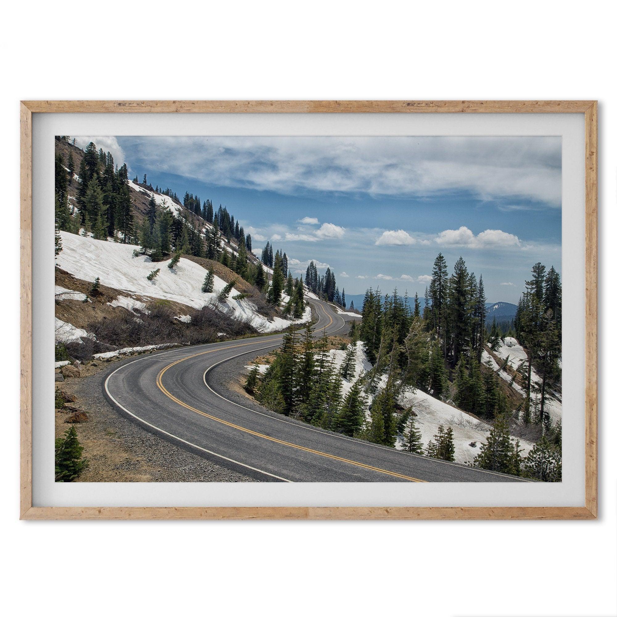 An unframed or framed fine art print of a mountain in Lassen National Park, Featuring a winding road through the lush forest and snow covered mountain.