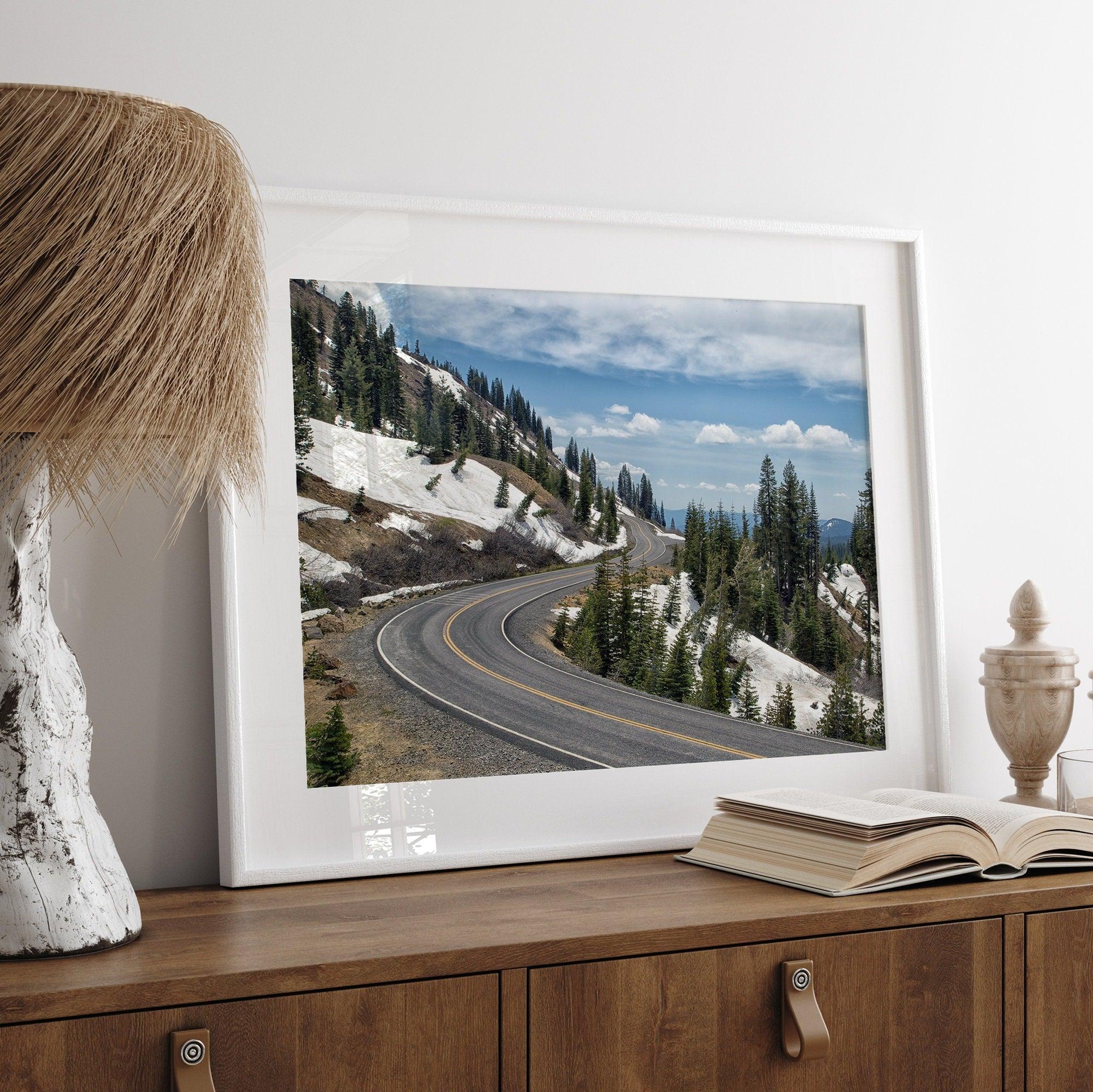 An unframed or framed fine art print of a mountain in Lassen National Park, Featuring a winding road through the lush forest and snow covered mountain.