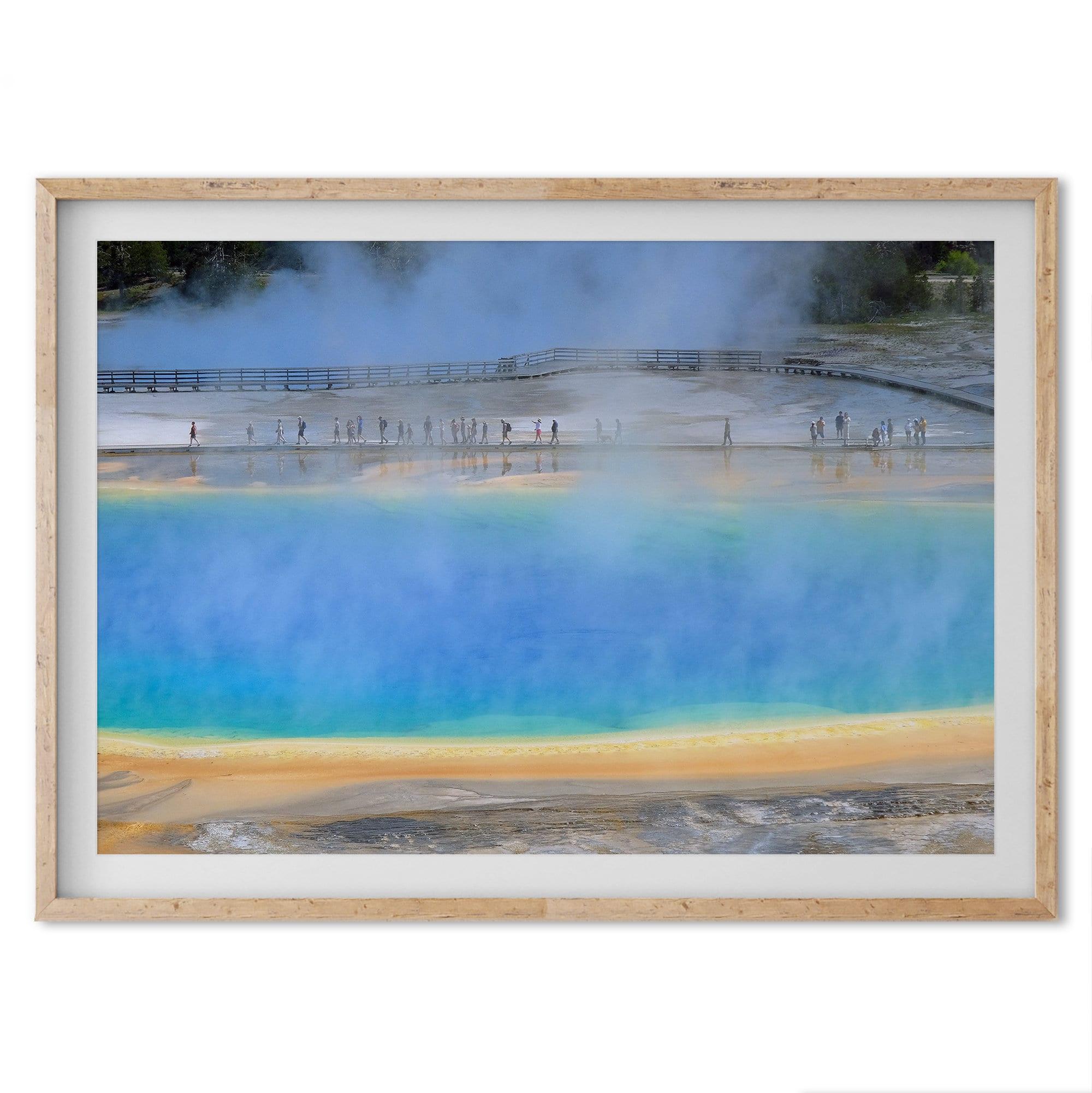 A fine art colorful photography print of Grand Prismatic Hot Springs in Yellowstone National Park. The picture shows the scale of the hot springs next to the people walking next to it.