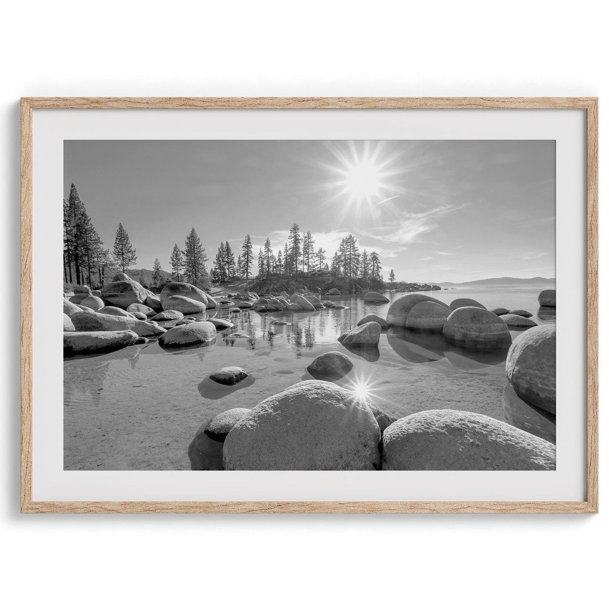 Capture the beauty of Lake Tahoe with this stunning black and white lake wall art. The image showcases majestic rocks rising from crystal-clear water. The reflection of the sun in the water adds a magical touch to the breathtaking scenery.