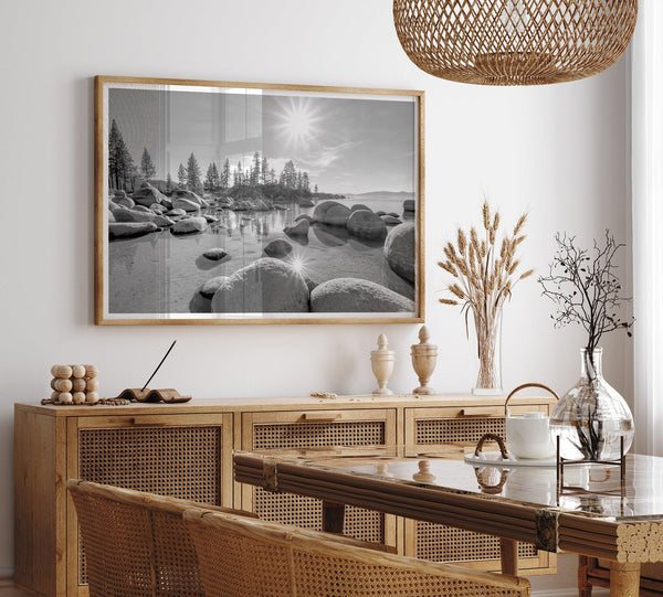 Capture the beauty of Lake Tahoe with this stunning black and white lake wall art. The image showcases majestic rocks rising from crystal-clear water. The reflection of the sun in the water adds a magical touch to the breathtaking scenery.