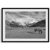A black and white mountain horse fine art print that can come framed on unframed and was taken in Peru. This mountain wall art showcases snow-covered mountains in Peru and a charming horse grazing relaxingly in the forefront of the picture.