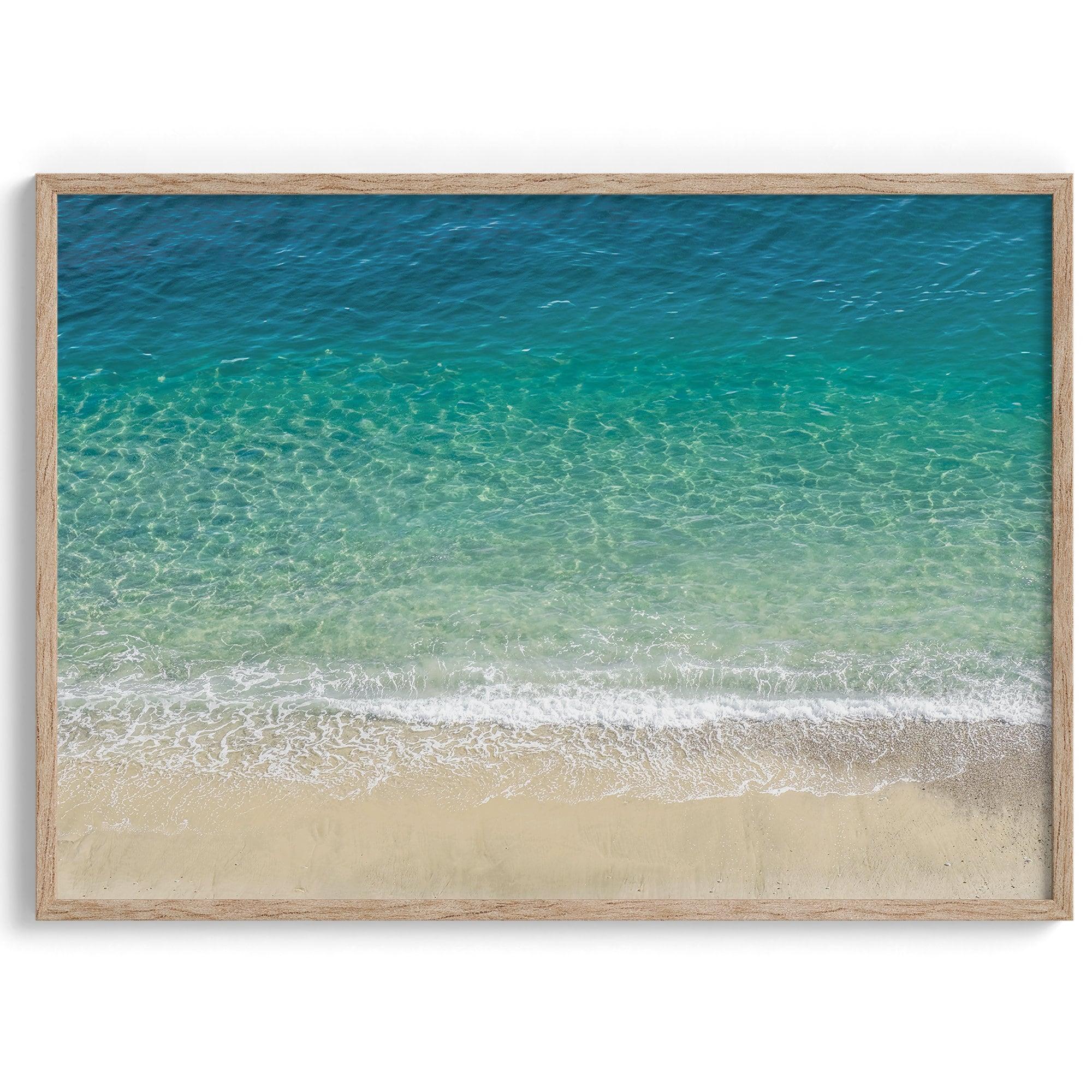 This fine art aerial beach print showcases the mesmerizing colors of the ocean in vivid detail. From the deep blue depths to the vibrant greenish turquoise blue, transitioning to the golden sandy beach and the crashing white surf.