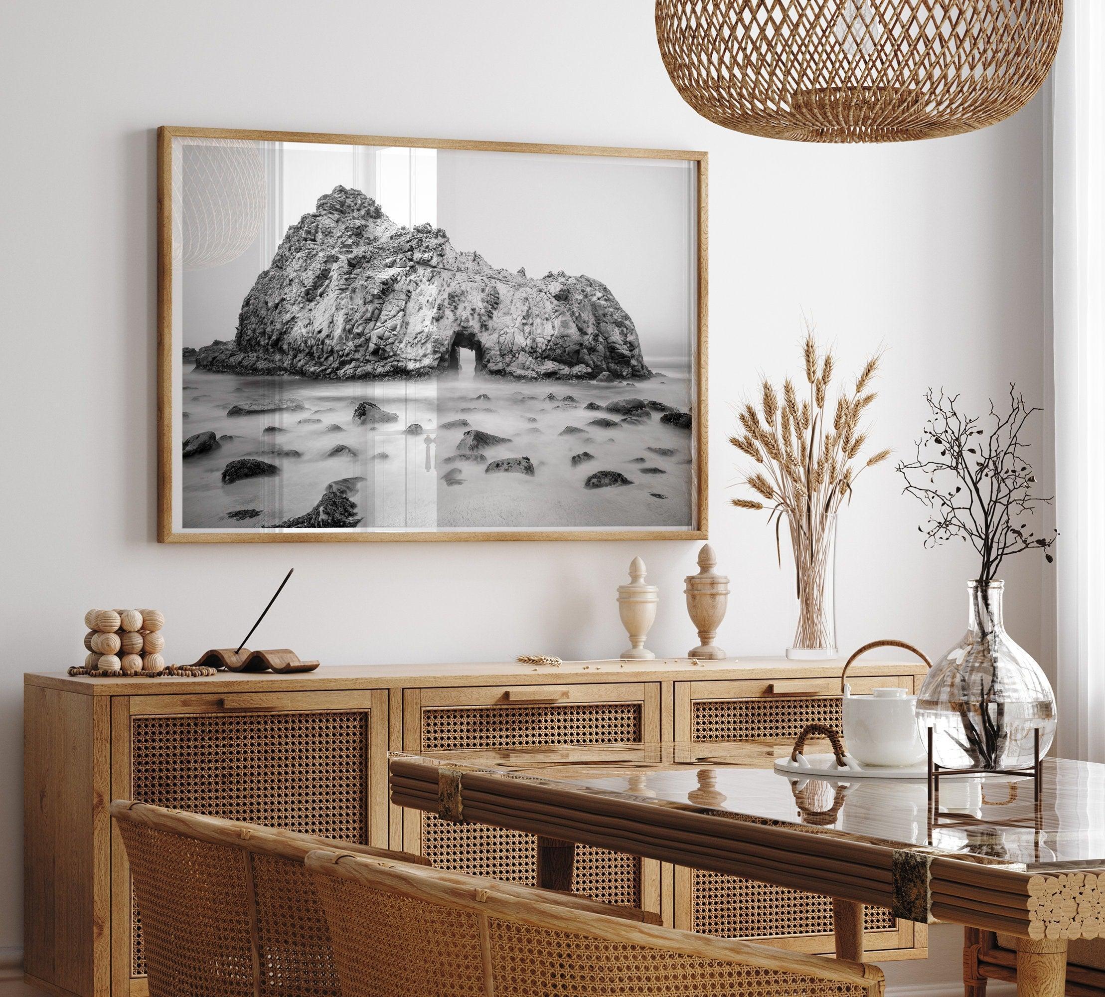 A fine art black and white print of Big Sur Pfeiffer Beach. This beach wall art shows a huge rock on the beach with an opening towards the open sea. This fine art photograph is shot in long exposure so the waves look creamy, gliding over the rocks