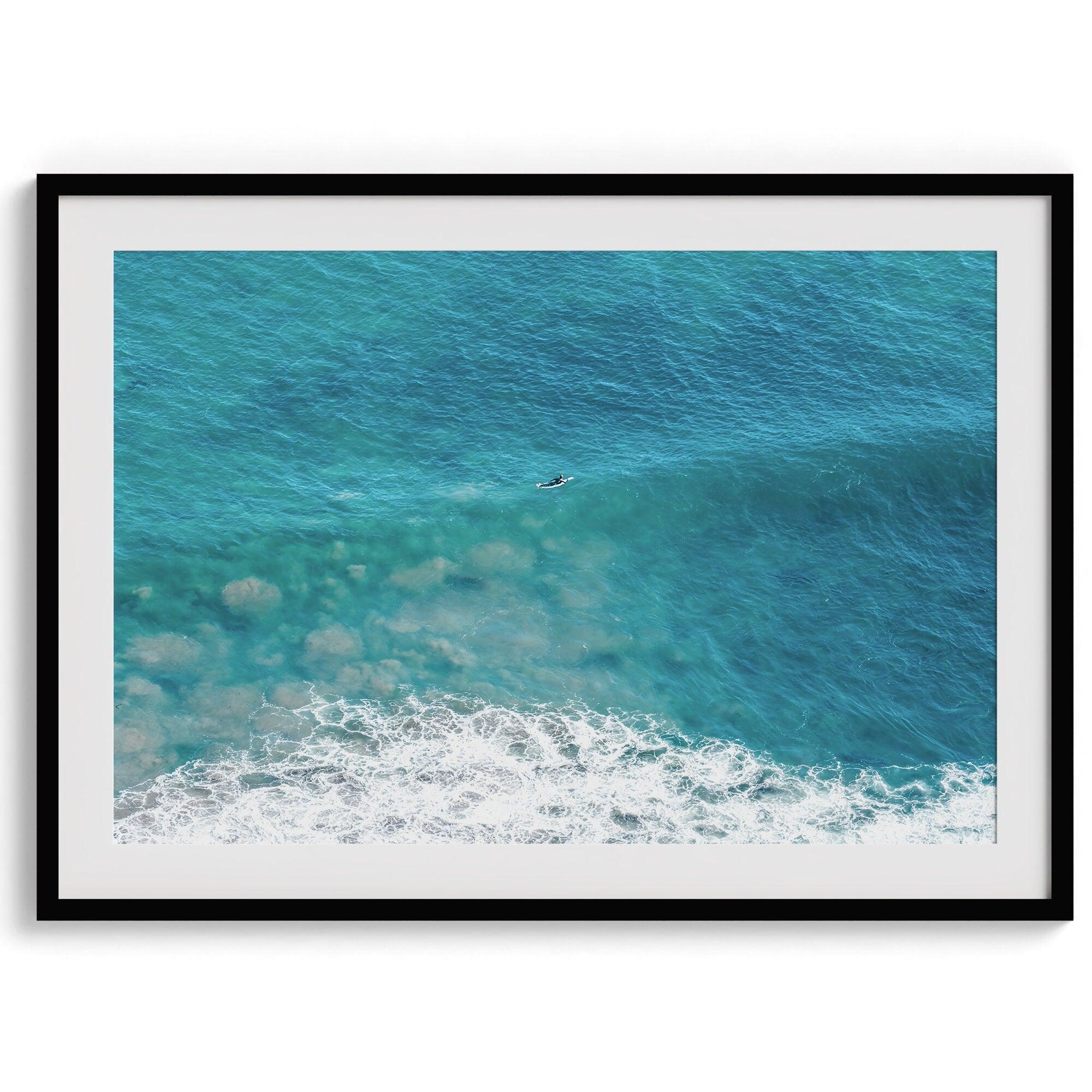 A fine art ocean print of an aerial beach showing a lone surfer with a large wave underneath.