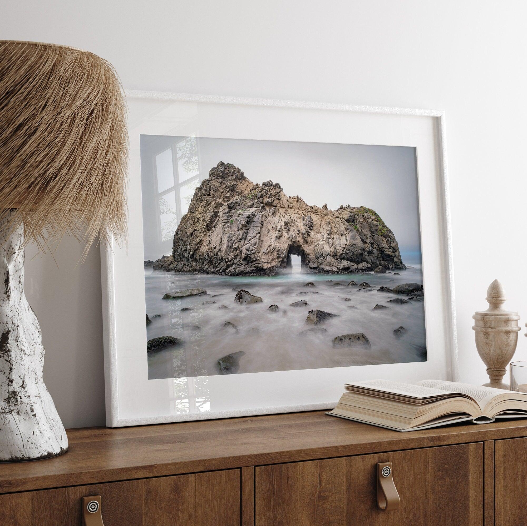 Fine art print showcasing a magnificent rock formation framing the horizon and crashing waves, with scattered rocks adding texture. Captivating and soothing, this print is a timeless addition to any space, evoking relaxation and awe-inspiring beauty.