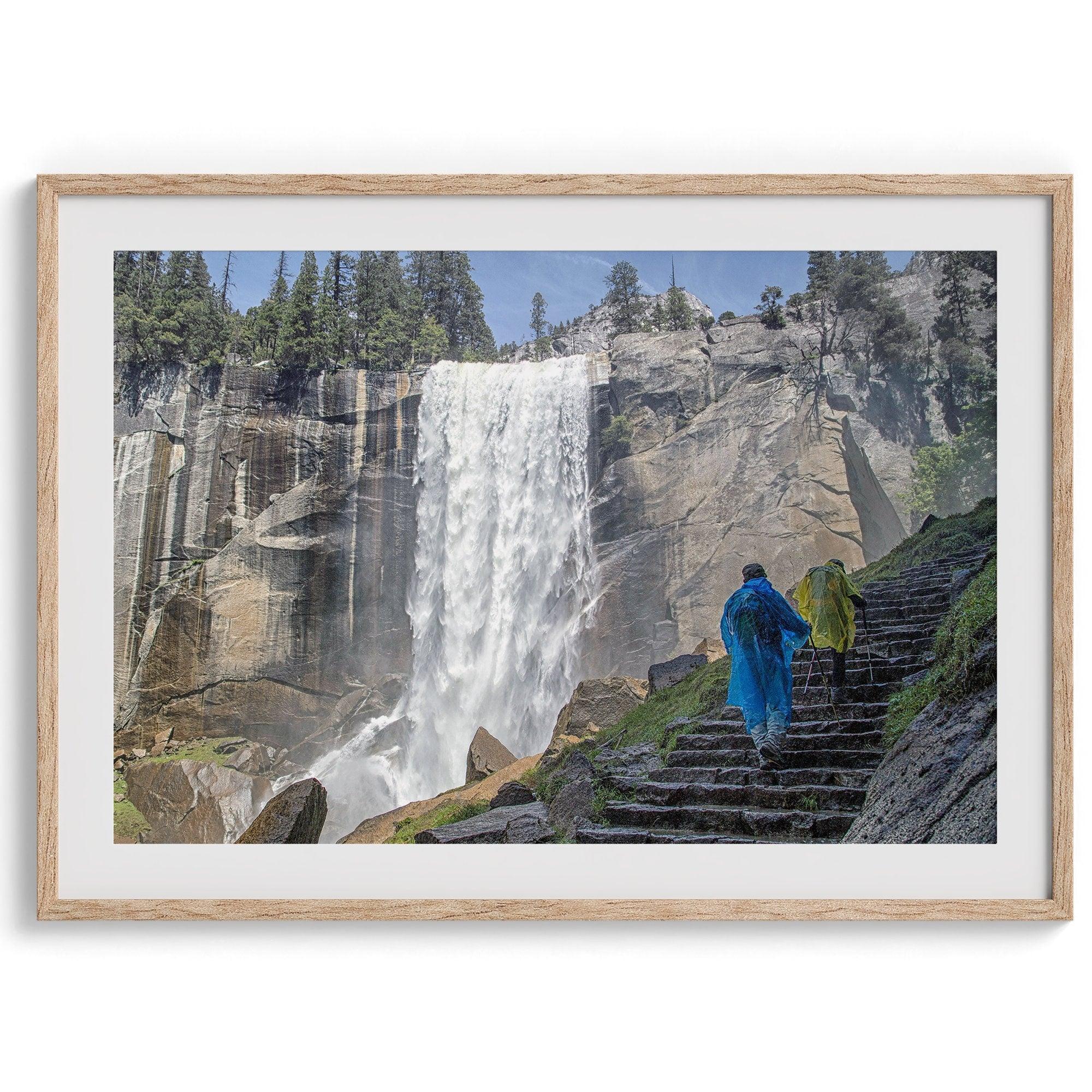 Climb the breathtaking Mist Trail in Yosemite National Part with this fine art waterfall nature print. This nature landscape wall art showcases the stunning gushing waterfall and the people scaling the trail with their colorful raincoats.