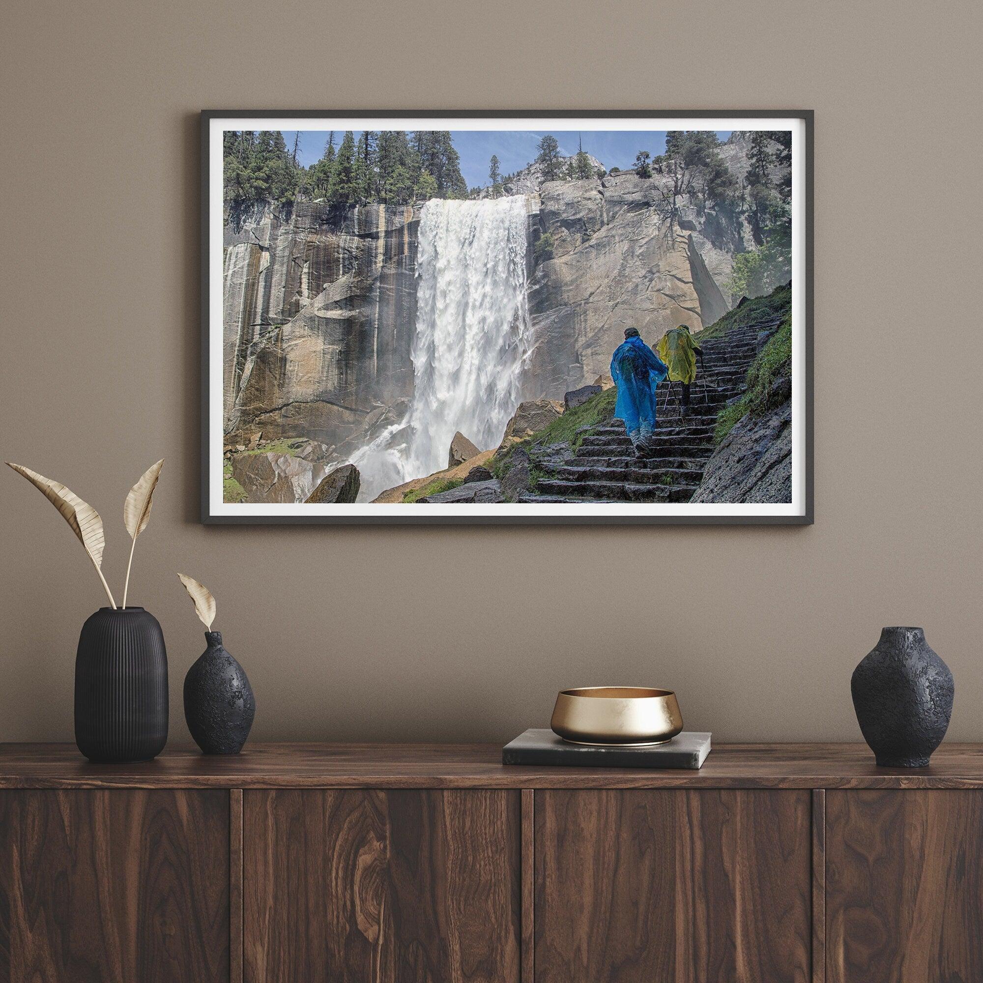 Climb the breathtaking Mist Trail in Yosemite National Part with this fine art waterfall nature print. This nature landscape wall art showcases the stunning gushing waterfall and the people scaling the trail with their colorful raincoats.