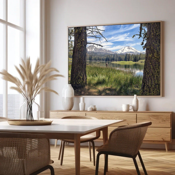 A stunning unframed or framed canvas print featuring a fisherman in Lassen National Park enjoying the tranquility of a serene lake nestled in the midst of towering snow-capped mountains.
