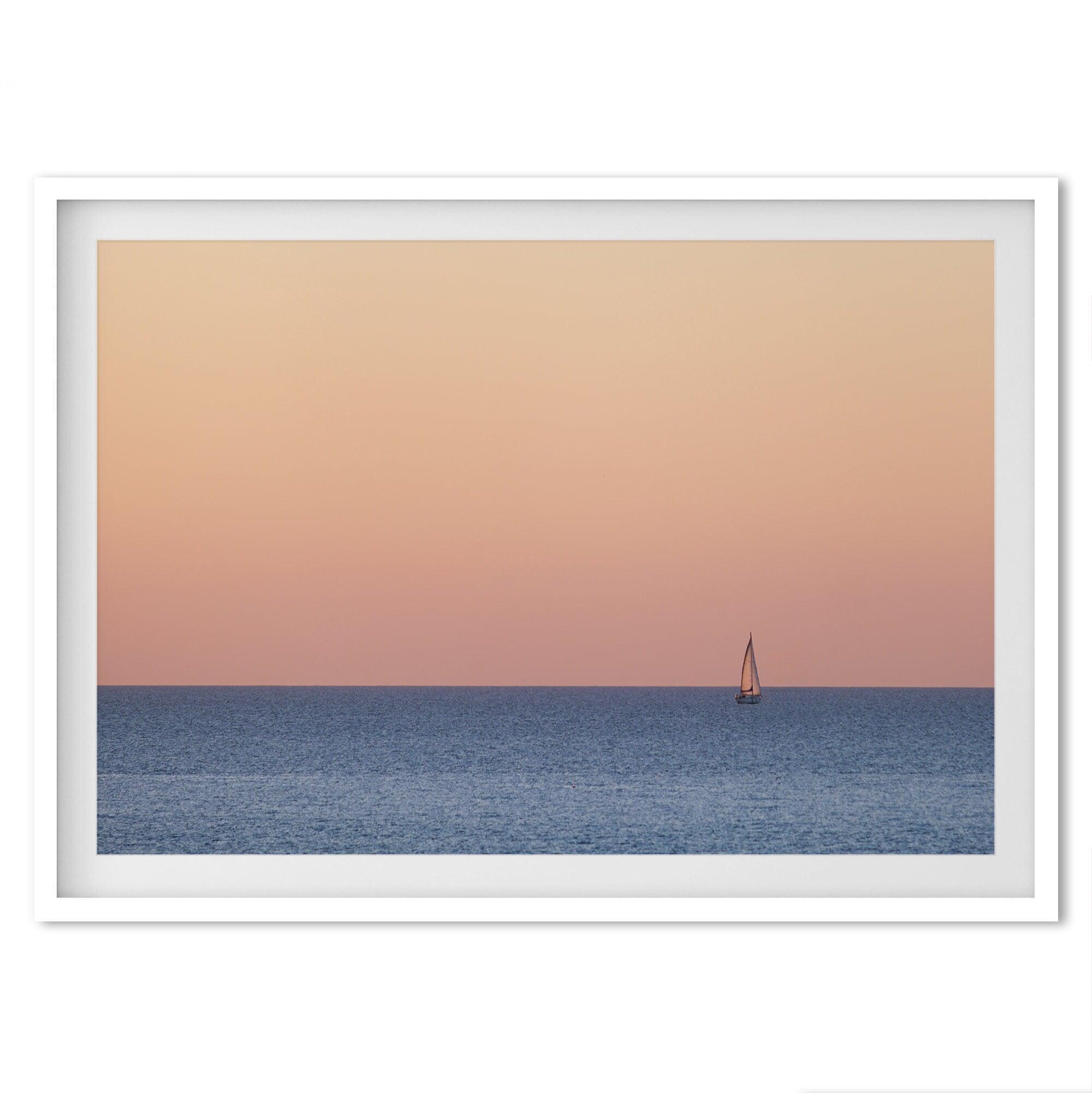 This stunning fine art ocean sunset photography print features a breathtaking scene of a boat against a golden and pink sky at sunset. The warm glow of the sunset and the natural beauty of the ocean and sky combine to create a soothing atmosphere.