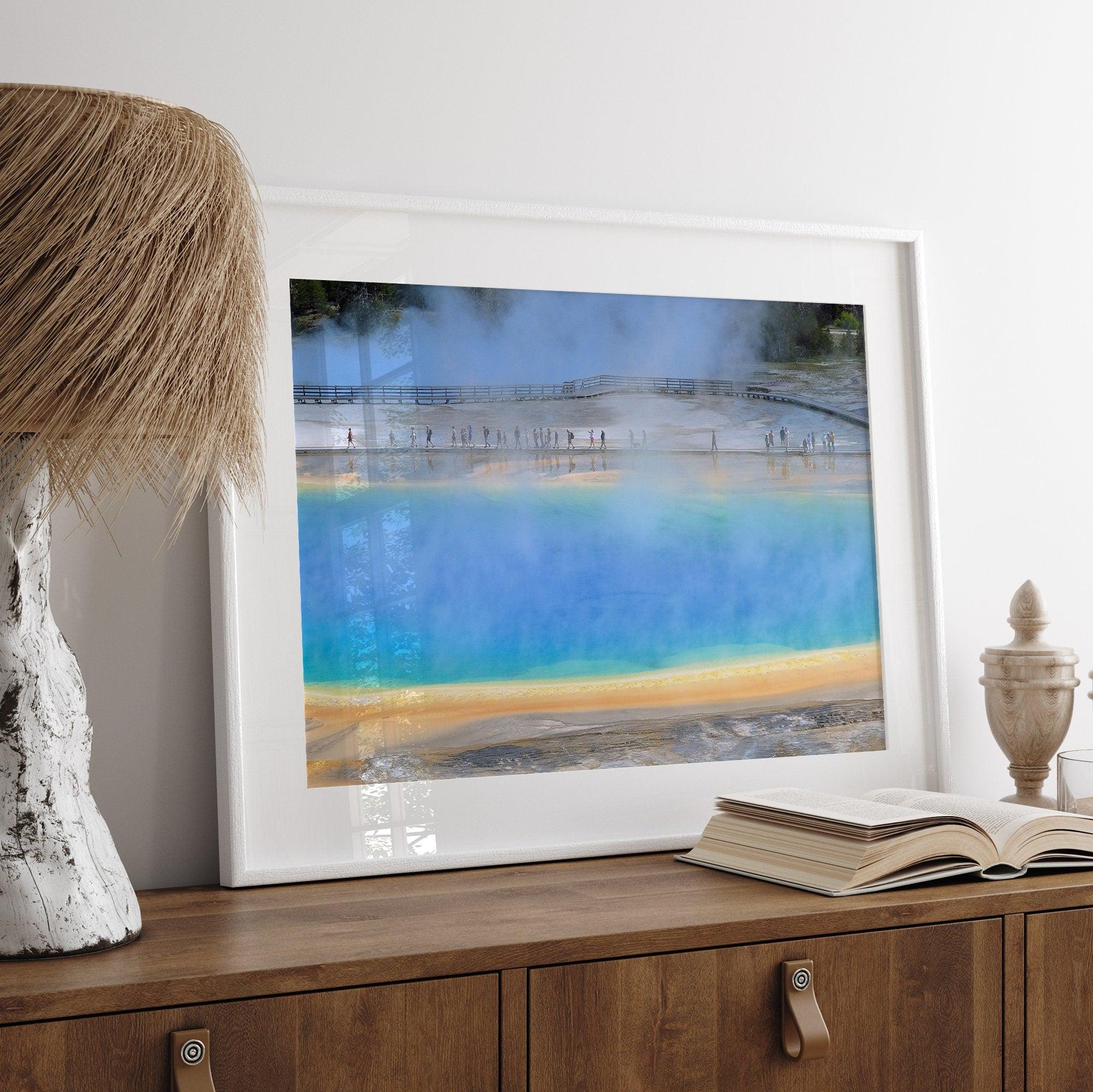 A fine art colorful photography print of Grand Prismatic Hot Springs in Yellowstone National Park. The picture shows the scale of the hot springs next to the people walking next to it.