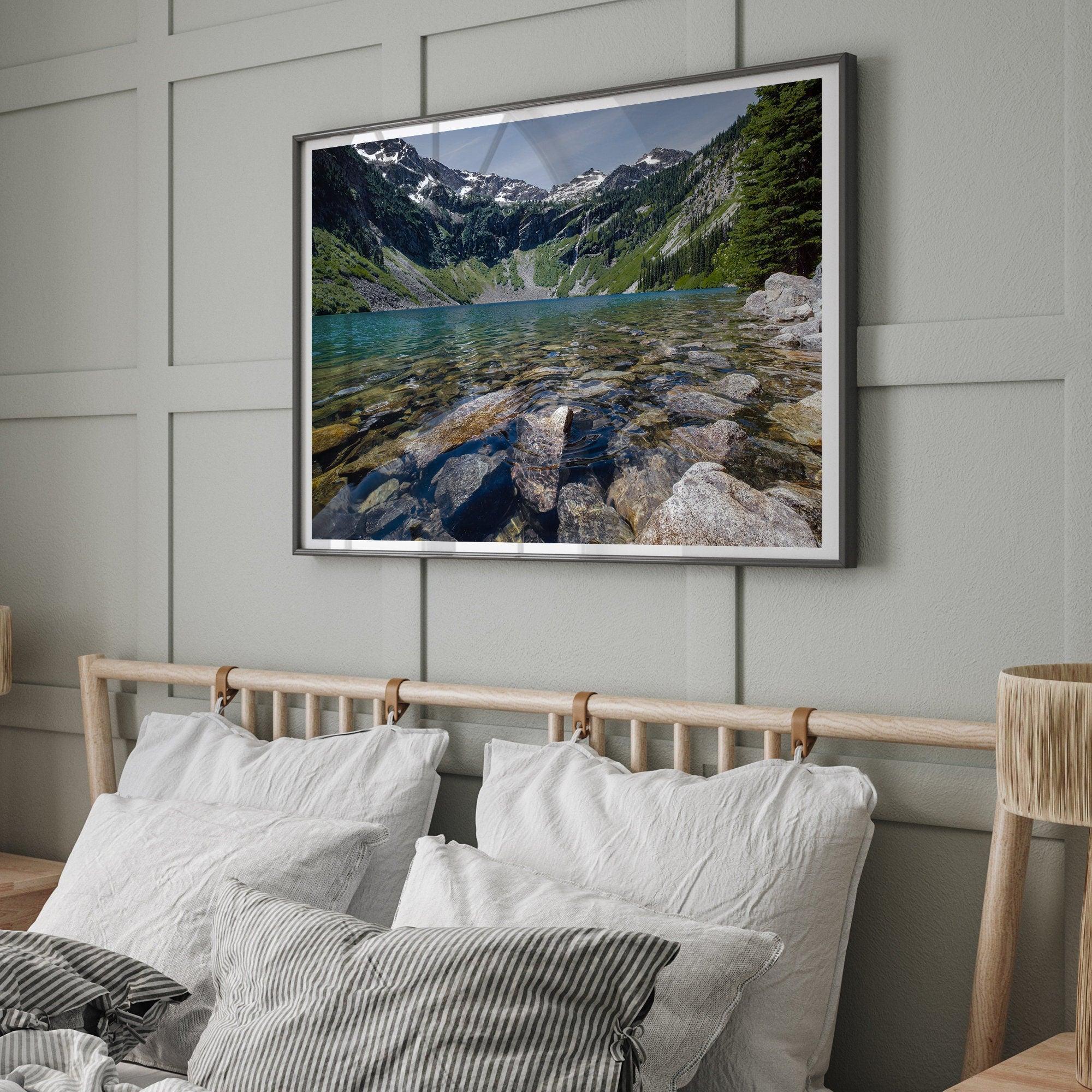 A fine art nature landscape framed print of blue lake in Washington State. The serene lake has vivid colors and clear water. So clear that you can see the stunning rocks at the bottom of the lake. In the backdrop, there are snow-covered mountains.