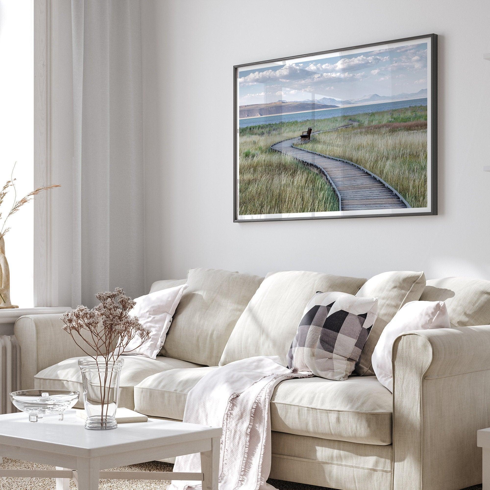 A fine art nature photography print featuring an inspiring winding path through the grassy wilderness of the eastern Sierra Nevada mountains toward Mono Lake. you can see the blue water of the lake in the background and a bench on the road.