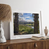 A framed or unframed mountain photo print capturing a fisherman fly fishing in a serene lake, with snow-capped mountains in the backdrop.