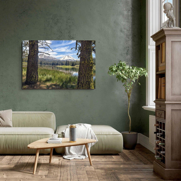 A stunning unframed or framed canvas print featuring a fisherman in Lassen National Park enjoying the tranquility of a serene lake nestled in the midst of towering snow-capped mountains.