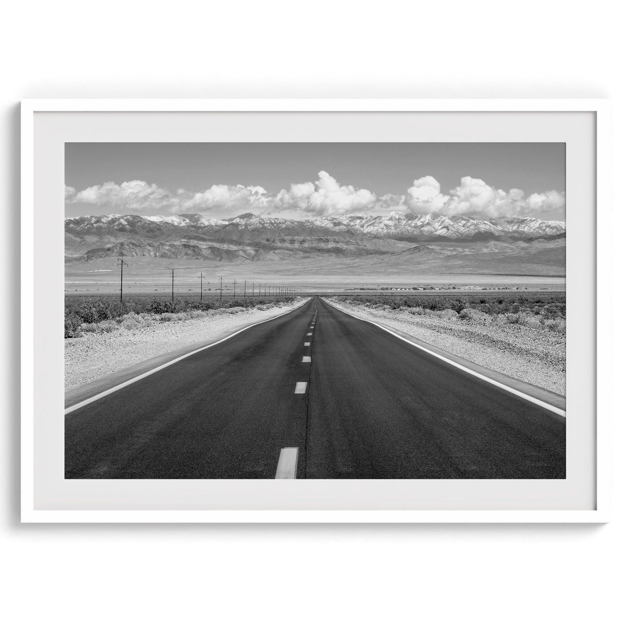 This stunning piece of black and white desert wall art will take your breath away. A beautifully framed picture of a Death Valley National Park road leading towards the snow-covered mountains at the end of the desert.