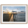 A fine art ocean sunset print featuring Pismo Beach Pier in Sunset with the surfers in the ocean and people enjoying a stroll on the pier.