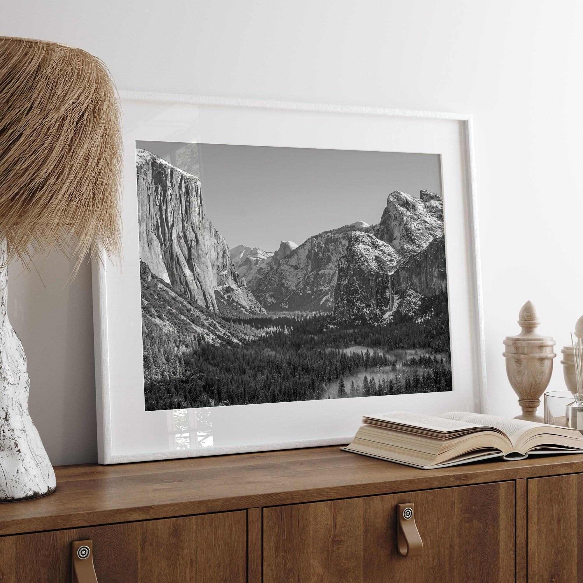 A fine art Yosemite Print featuring Yosemite Valley covered in snow in winter and a beautiful fog lays in the valley forest. This black and white mountain wall art is perfect for nature and fine art lovers.