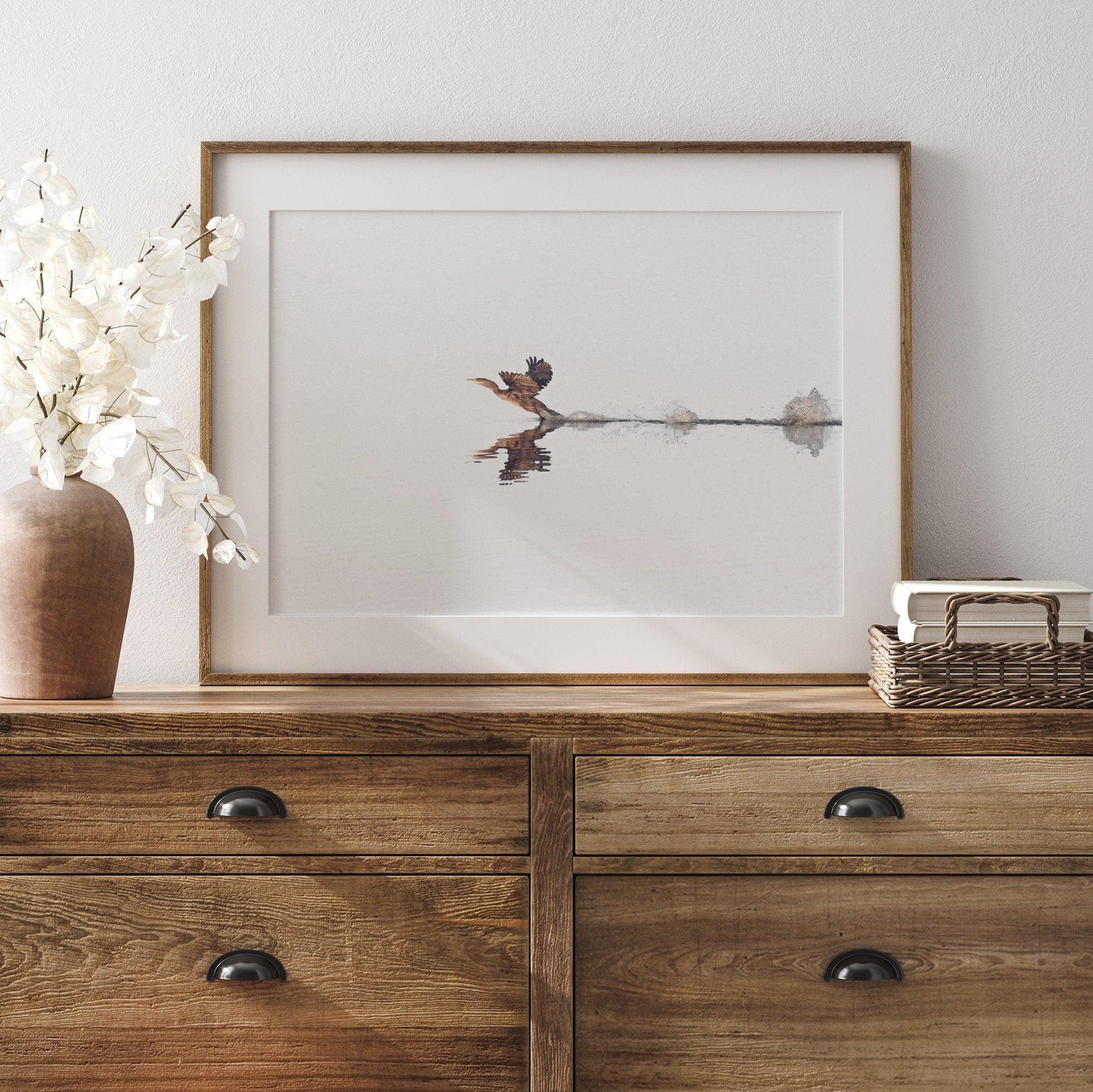 A fine art minimalist wildlife photography print showcasing a bird flying over a lake in Arizona.