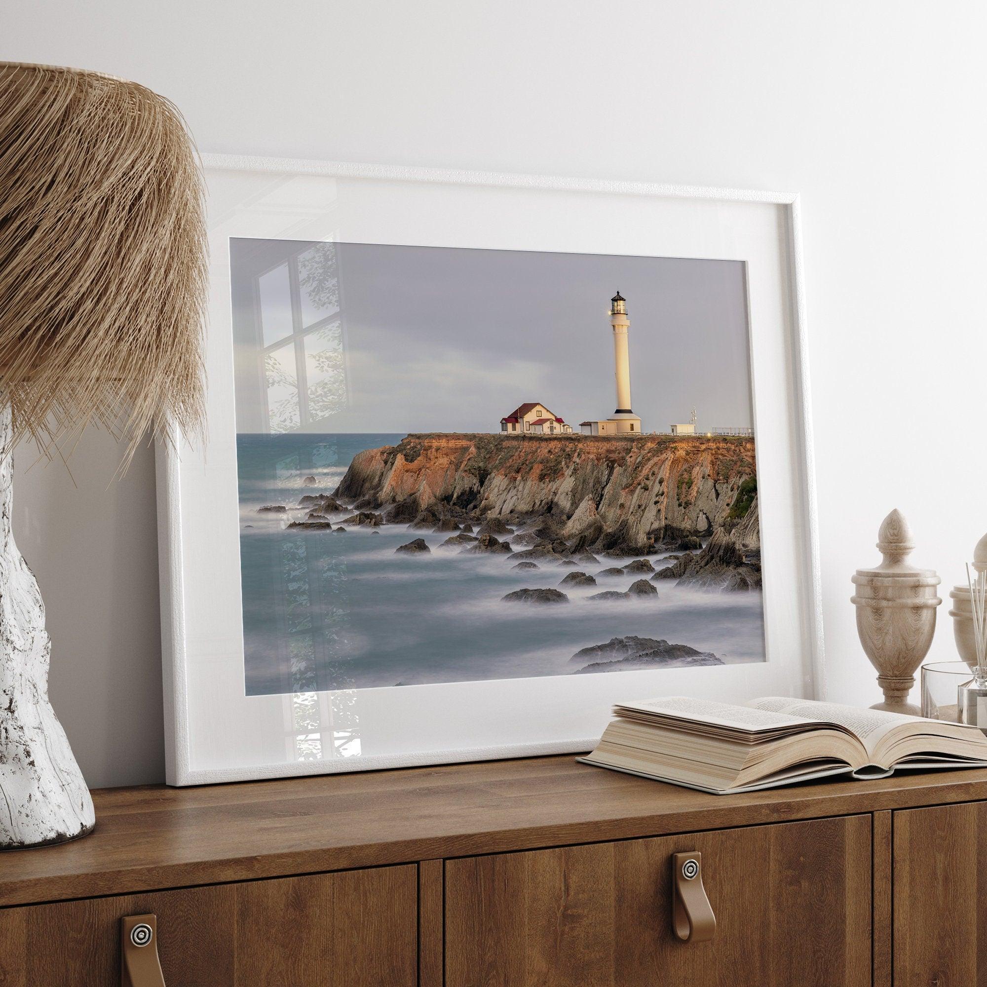 Long exposure fine art photography print of Pigeon Point Lighthouse at sunset. Golden light illuminates the lighthouse and cliffs, while the ocean surf crashes against the rocks in a creamy blur.