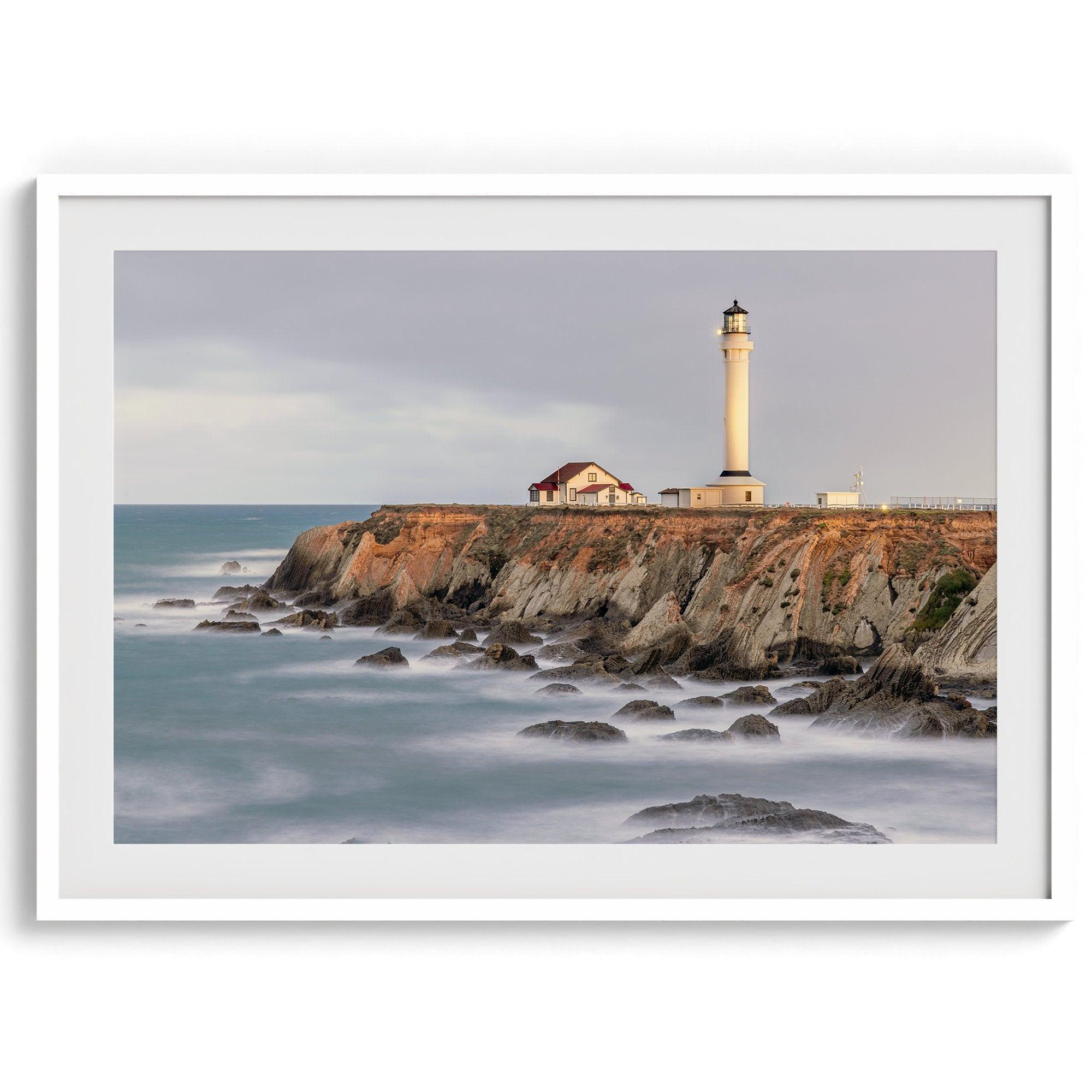 Long exposure fine art photography print of Pigeon Point Lighthouse at sunset. Golden light illuminates the lighthouse and cliffs, while the ocean surf crashes against the rocks in a creamy blur.